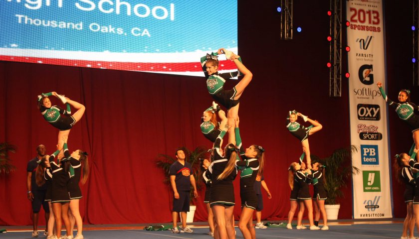 BODY LINES—The cheer team performs its competitions piece, composed of stunts, tumbling and dance segments, at the Anaheim Convention Center as three of its members arch their backs into the scorpion form.