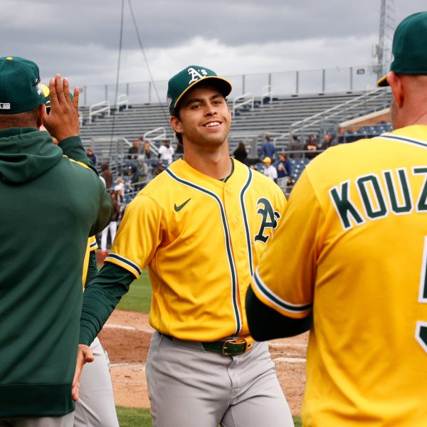 TAKING THE FIELD - Max Muncy cheerfully high-fives his coaches after a successful inning during Spring Training preparing for the season.